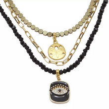 Cargar imagen en el visor de la galería, Collar triple de Ónix, Hematita y cadena con dijes de Ojo Protector y Galleta de Mar. Aretes a juego incluídos.