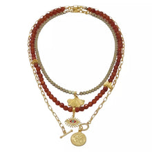 Cargar imagen en el visor de la galería, Collar triple de Cornalina, Hematita y cadena con Ojo Protector, hoja de la fortuna y símbolo OM. Aretes a juego incluidos.